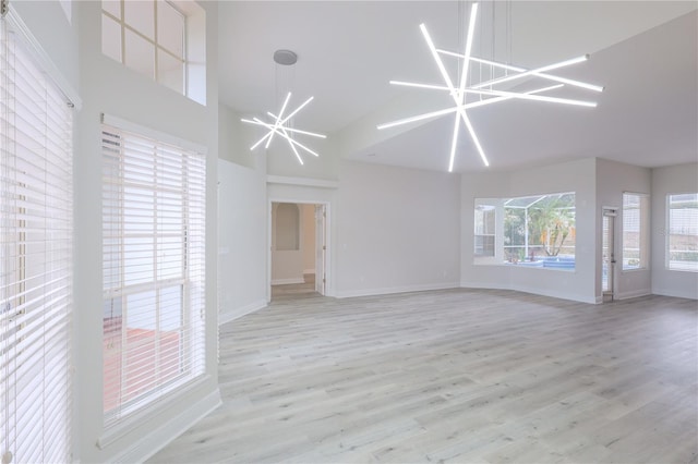 8023 Canyon Lake Cir, Orlando, FL 32835 - unfurnished living room with a chandelier, high vaulted ceiling, light wood-type flooring, and baseboards
