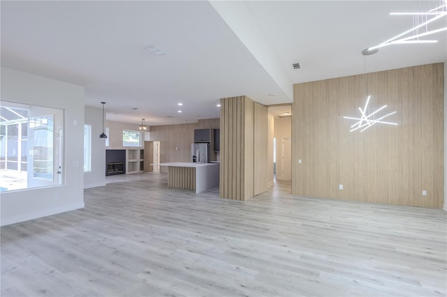 8023 Canyon Lake Cir, Orlando, FL 32835 - unfurnished living room featuring light wood-type flooring, wood walls, recessed lighting, and a glass covered fireplace