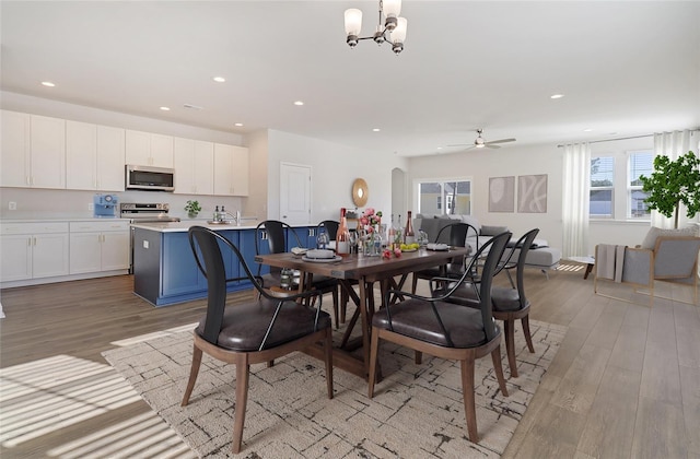 dining room with light wood finished floors, recessed lighting, and ceiling fan with notable chandelier