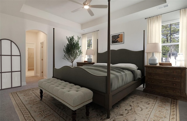 bedroom with arched walkways, light carpet, multiple windows, and visible vents