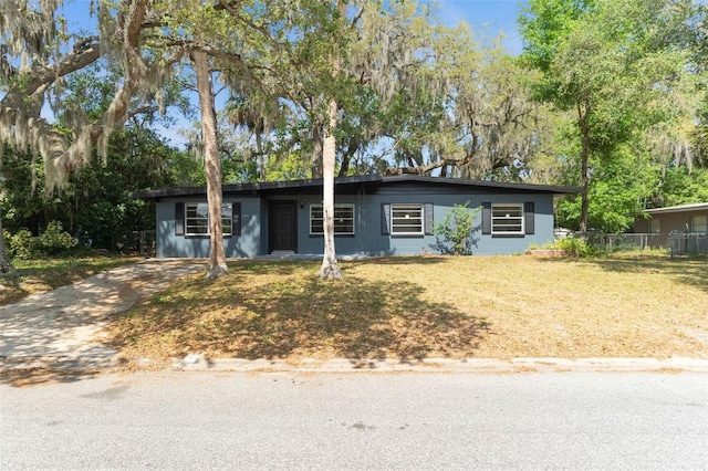 single story home featuring concrete block siding, a front lawn, and fence