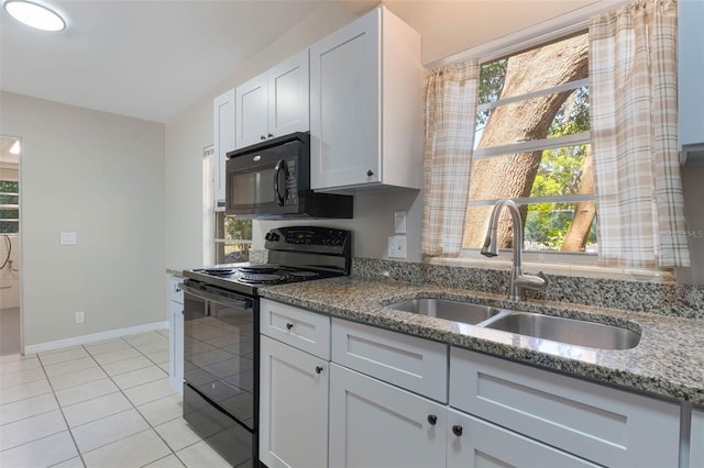 kitchen with light stone countertops, white cabinets, black appliances, light tile patterned flooring, and a sink