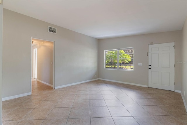 empty room featuring light tile patterned floors, baseboards, and visible vents