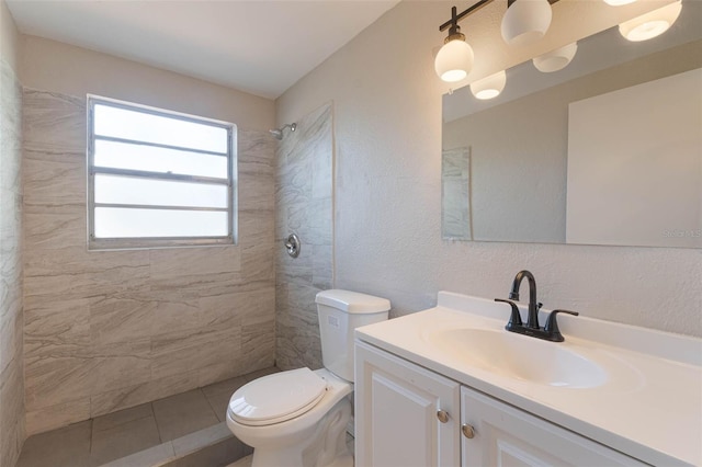 full bathroom featuring tile patterned floors, vanity, a tile shower, and toilet