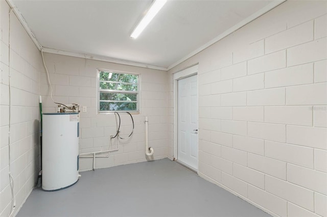below grade area with electric water heater and concrete block wall