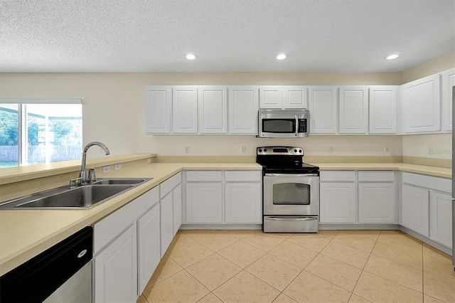 kitchen featuring recessed lighting, light tile patterned floors, white cabinets, stainless steel appliances, and a sink
