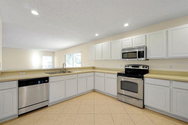 kitchen with white cabinetry, appliances with stainless steel finishes, light tile patterned flooring, light countertops, and a sink
