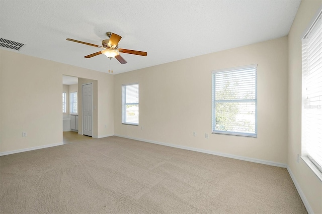 unfurnished room with visible vents, baseboards, a ceiling fan, a textured ceiling, and light carpet