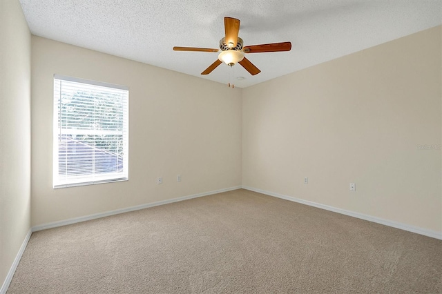 carpeted empty room with ceiling fan, baseboards, and a textured ceiling