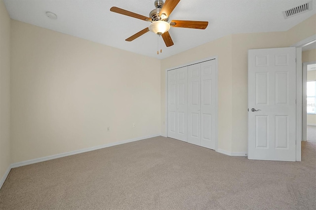 unfurnished bedroom with a closet, baseboards, visible vents, ceiling fan, and carpet