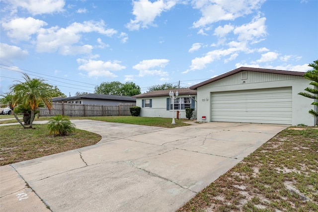 ranch-style house with concrete driveway, stucco siding, fence, and a garage