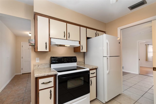 kitchen featuring visible vents, range with electric cooktop, light countertops, freestanding refrigerator, and under cabinet range hood