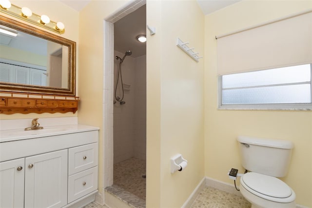 full bath featuring baseboards, a tile shower, toilet, vanity, and tile patterned floors