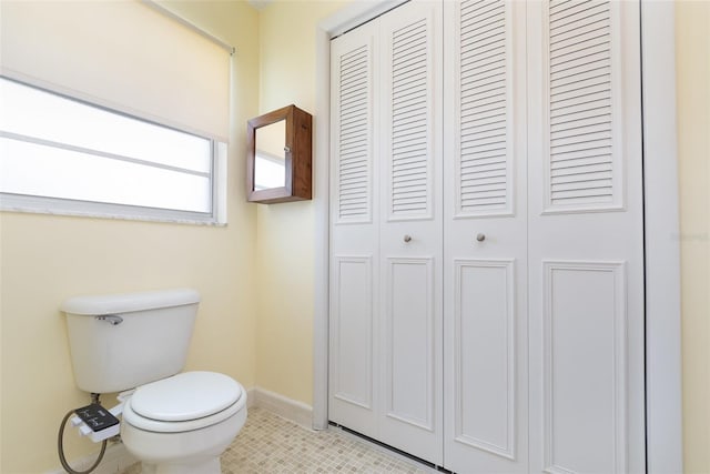 bathroom featuring toilet, tile patterned floors, a closet, and baseboards