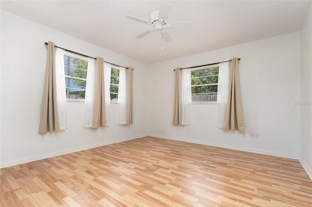 empty room featuring light wood-style flooring, a healthy amount of sunlight, baseboards, and a ceiling fan