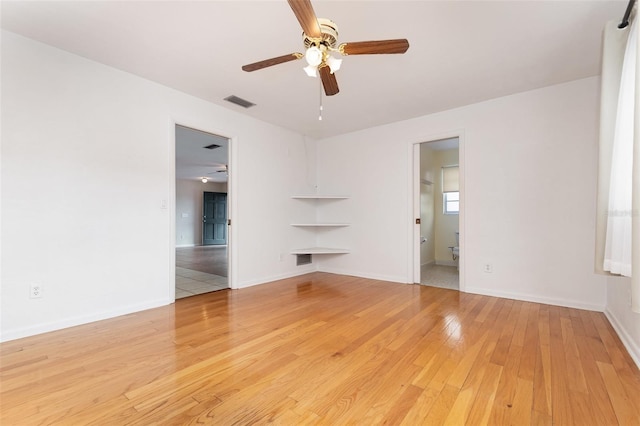 spare room with light wood-type flooring, ceiling fan, baseboards, and visible vents