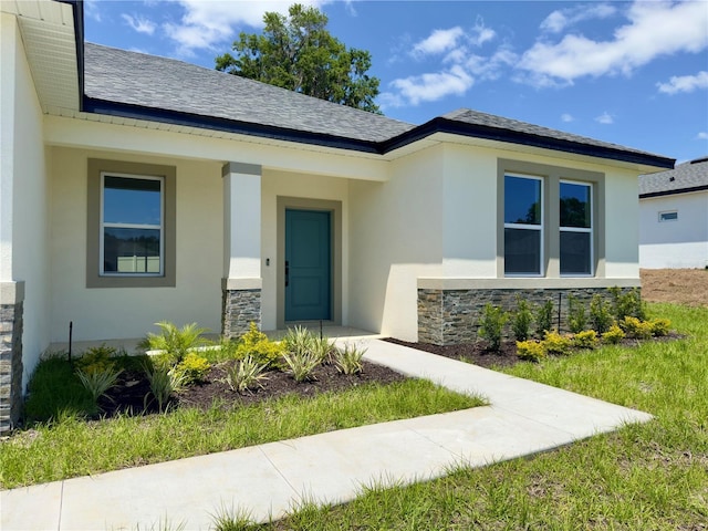 view of exterior entry featuring stone siding and stucco siding