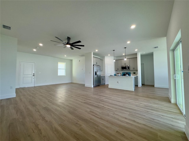 unfurnished living room with recessed lighting, ceiling fan, light wood-style flooring, and baseboards