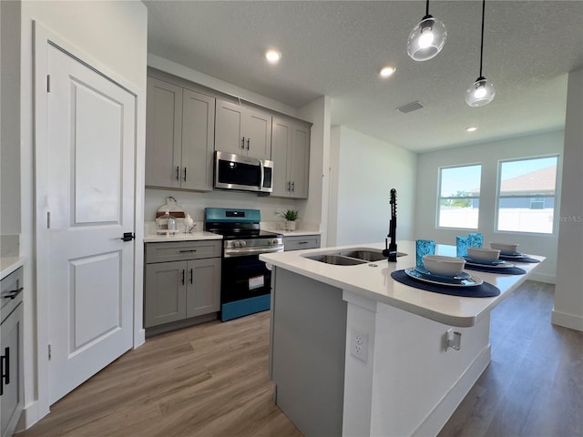 kitchen featuring stainless steel appliances, gray cabinets, a sink, light wood-style floors, and recessed lighting