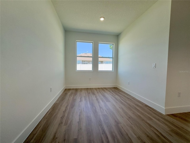 spare room with wood finished floors, baseboards, and a textured ceiling