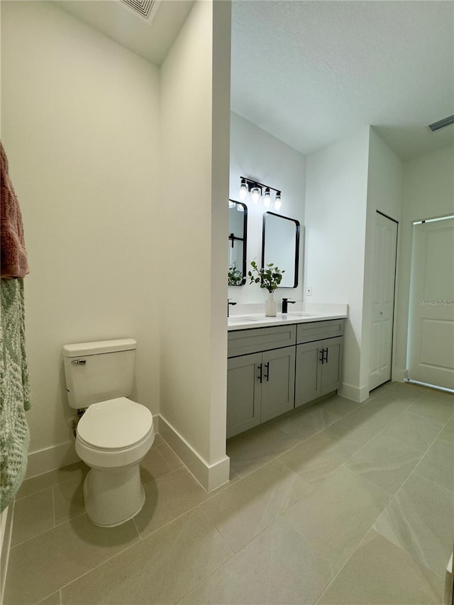bathroom with baseboards, toilet, vanity, and tile patterned floors