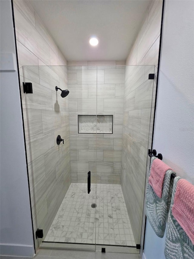 full bathroom featuring a shower stall and baseboards