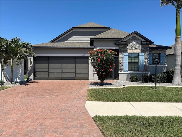 2137 Apian Way, Port Charlotte, FL 33953 - view of front of home featuring a garage, decorative driveway, stone siding, stucco siding, and roof with shingles