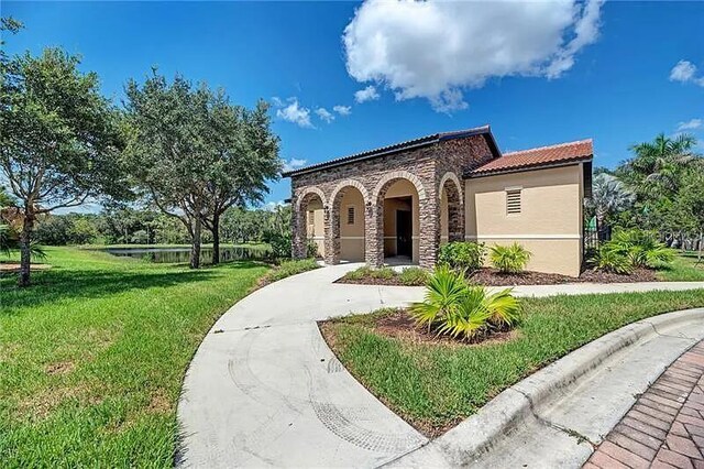 2137 Apian Way, Port Charlotte, FL 33953 - mediterranean / spanish home featuring a front lawn, stone siding, a tiled roof, stucco siding, and a water view