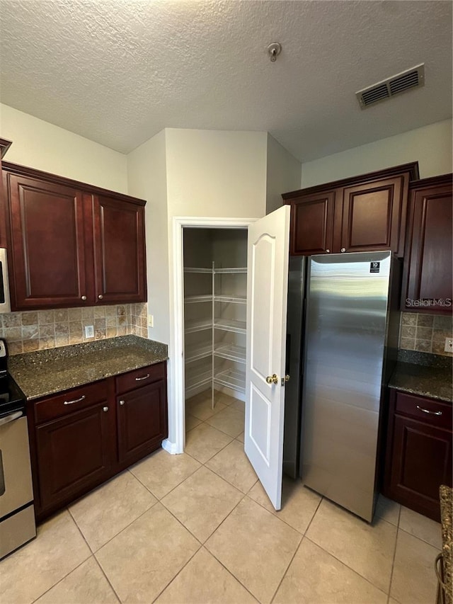 2125 Betsy Ross Ln, Saint Cloud, FL 34769 - kitchen featuring dark stone counters, light tile patterned floors, tasteful backsplash, visible vents, and appliances with stainless steel finishes