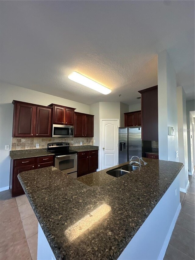 2125 Betsy Ross Ln, Saint Cloud, FL 34769 - kitchen featuring dark stone counters, light tile patterned floors, tasteful backsplash, a sink, and stainless steel appliances