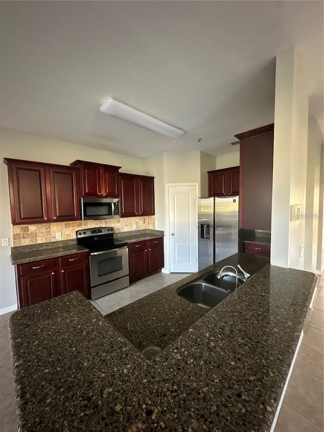 2125 Betsy Ross Ln, Saint Cloud, FL 34769 - kitchen with dark stone counters, tasteful backsplash, dark brown cabinets, appliances with stainless steel finishes, and a sink