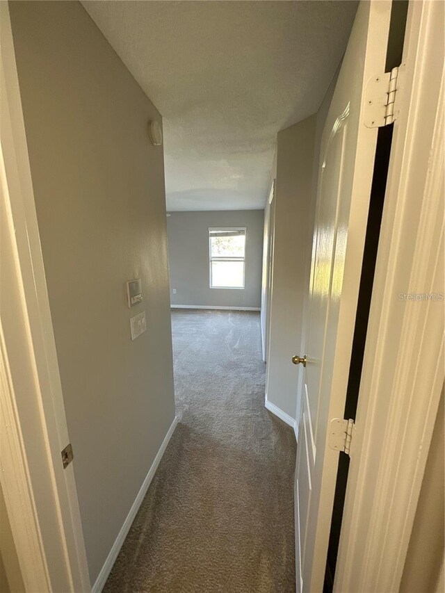 2125 Betsy Ross Ln, Saint Cloud, FL 34769 - hallway featuring baseboards, dark colored carpet, and a textured ceiling