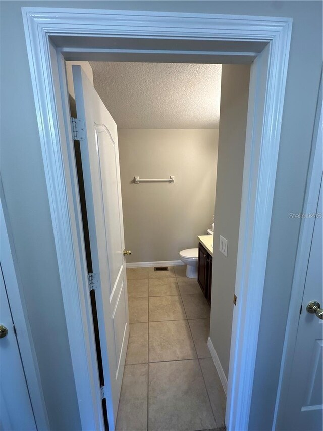 2125 Betsy Ross Ln, Saint Cloud, FL 34769 - bathroom featuring vanity, baseboards, tile patterned floors, a textured ceiling, and toilet
