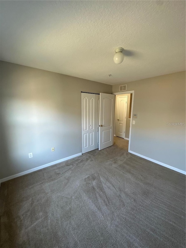 2125 Betsy Ross Ln, Saint Cloud, FL 34769 - unfurnished bedroom featuring visible vents, baseboards, a closet, dark carpet, and a textured ceiling