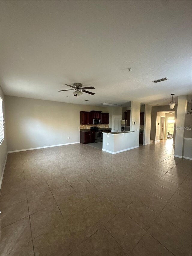 2125 Betsy Ross Ln, Saint Cloud, FL 34769 - unfurnished living room featuring dark tile patterned flooring, baseboards, a ceiling fan, and visible vents