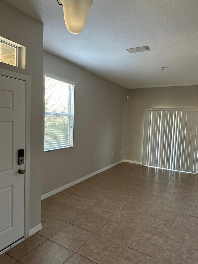 2125 Betsy Ross Ln, Saint Cloud, FL 34769 - unfurnished room with tile patterned flooring, visible vents, a textured ceiling, and baseboards