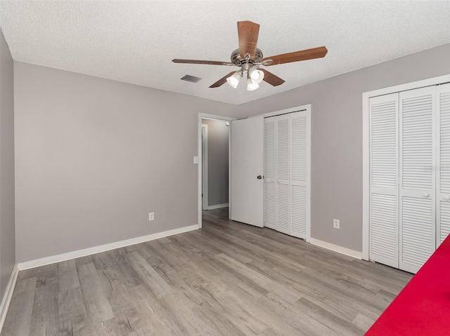 490 Burnt Tree Ln, Apopka, FL 32712 - unfurnished bedroom featuring a textured ceiling, two closets, baseboards, wood finished floors, and visible vents