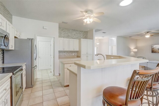 1900 NW 57th Ct, Ocala, FL 34482 - kitchen with a ceiling fan, appliances with stainless steel finishes, a kitchen breakfast bar, light tile patterned floors, and a center island with sink