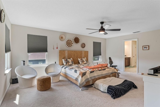 bedroom featuring visible vents, a ceiling fan, a textured ceiling, connected bathroom, and light carpet