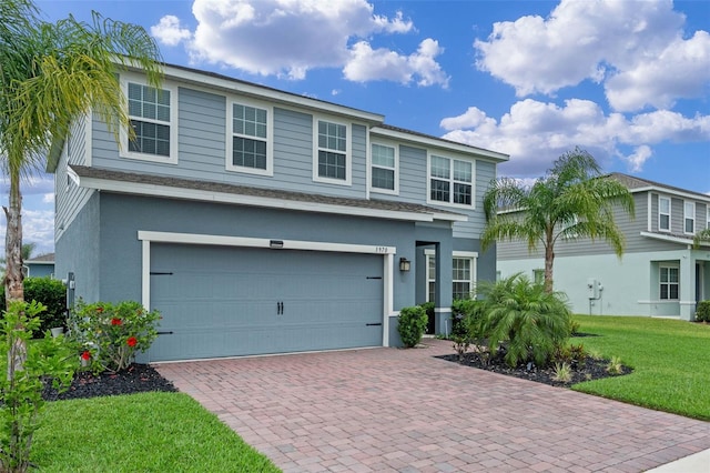traditional-style home featuring a front yard, an attached garage, decorative driveway, and stucco siding
