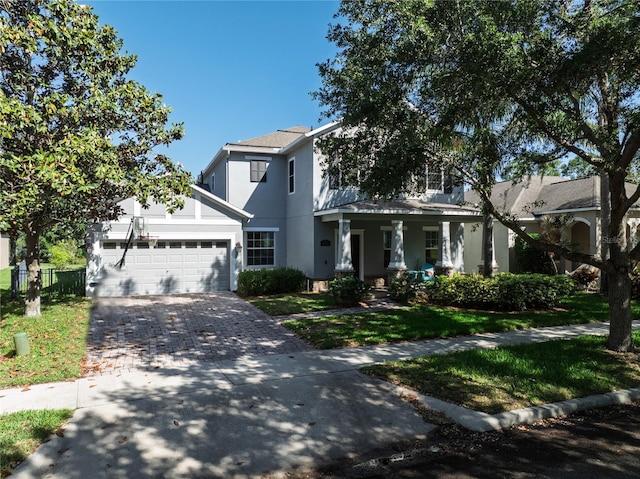 view of front of property featuring a porch, stucco siding, an attached garage, decorative driveway, and a front lawn