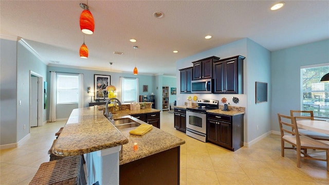 kitchen featuring appliances with stainless steel finishes, a sink, ornamental molding, healthy amount of natural light, and a large island with sink