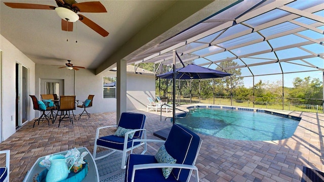 view of swimming pool featuring ceiling fan, a patio area, outdoor dining area, glass enclosure, and fence