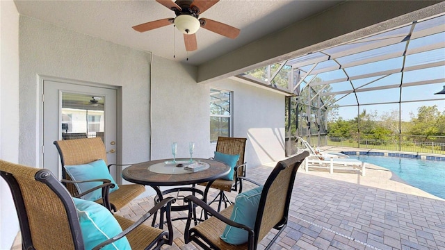view of patio / terrace with ceiling fan, an outdoor pool, and glass enclosure