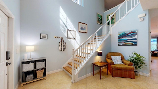 stairs featuring a towering ceiling, tile patterned flooring, and baseboards