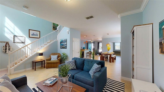 living area featuring stairway, light tile patterned floors, crown molding, and baseboards