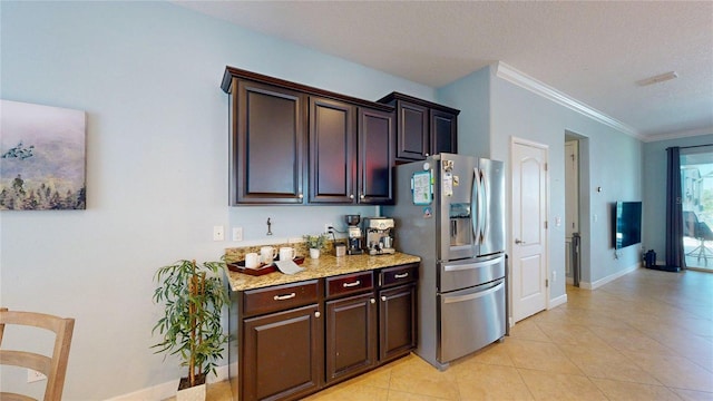 kitchen with stainless steel refrigerator with ice dispenser, light tile patterned floors, crown molding, dark brown cabinetry, and light stone countertops