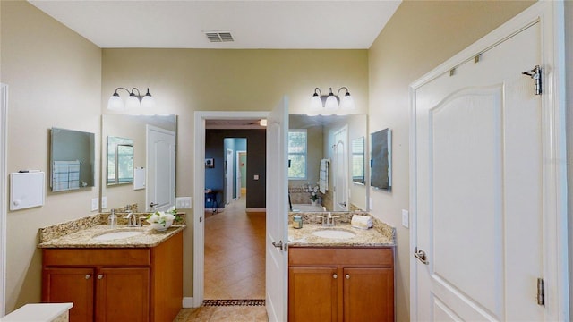bathroom featuring tile patterned flooring, two vanities, baseboards, and healthy amount of natural light
