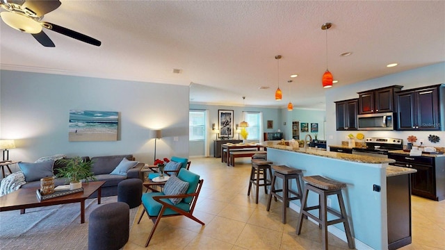 kitchen featuring stainless steel appliances, open floor plan, a breakfast bar area, light stone counters, and a kitchen island with sink