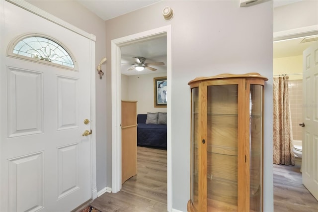 entryway with baseboards, light wood finished floors, and ceiling fan